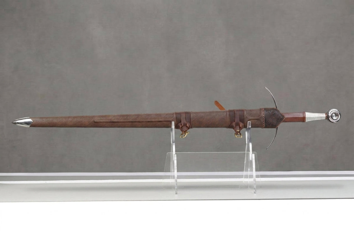 Crownforged Langschwert : Langschwert in der Scheide in braune Lederscheide mit Messingschnallen und Stahlknauf vor grauem Hintergrund